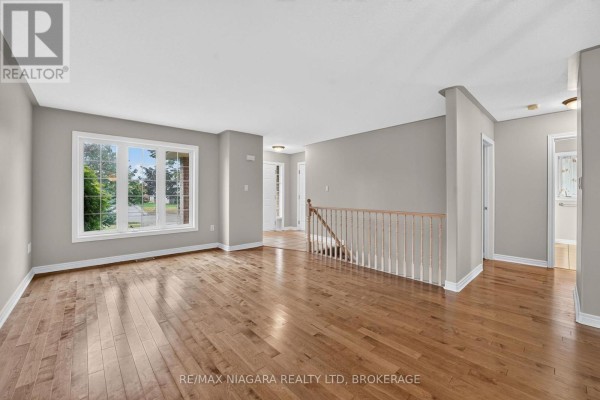 Living room with hardwood floors, gray walls, a large window, and a view of the entryway. - 15 Days Avenue, Welland