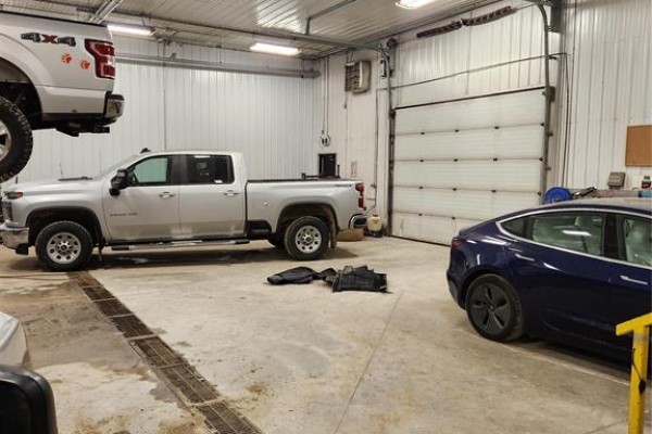 Interior of a garage with two vehicles, high ceilings, and a clean concrete floor - 15 Dielmann Drive, Headingley