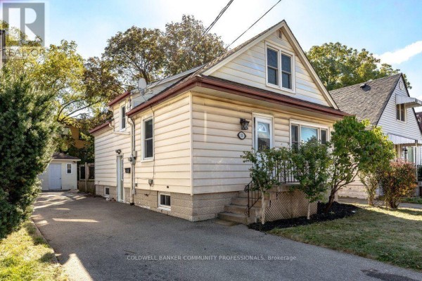 Exterior of a light beige house with a driveway, a small shed, and front steps. - 15 East 27th Street, Hamilton