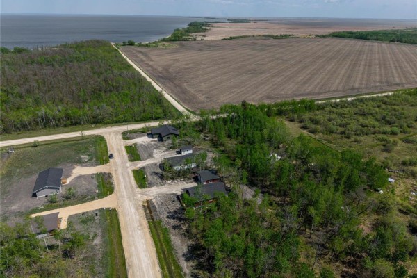 Aerial view of a rural development with houses, trees, fields, and a lake. - 15 Everwood Crescent, Matlock