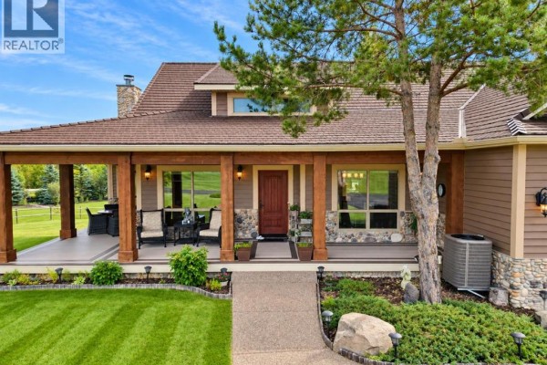 Front porch of the house with seating area, stone accents, and a large wooden door. - 15 Gray Way, Rural Rocky View County