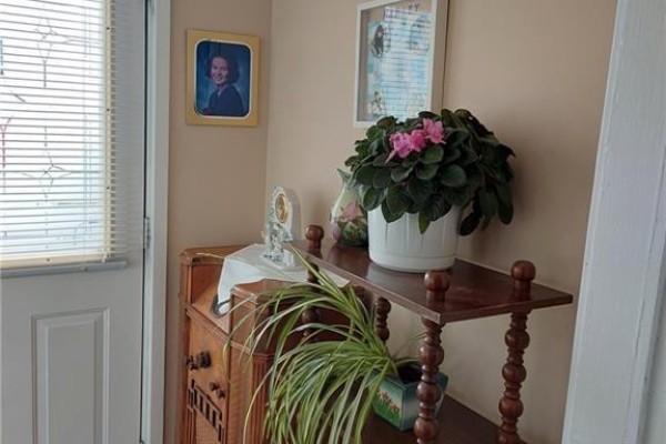 Living room showing a sofa, entryway to stairs, and a pass-through window with a desk visible. - 15 Green Street, Saint John