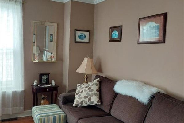 Kitchen with white cabinets, stainless steel double sink, and a window with fruit-patterned curtains. - 15 Green Street, Saint John