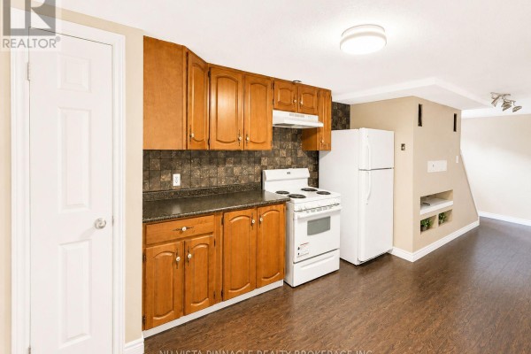 Kitchen with wooden cabinets, white appliances, and dark laminate floor - 15 Gregory Place St  Thomas