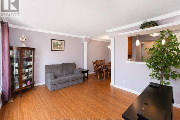 Living room with a gray sofa, a view of the dining area, and hardwood floors throughout. - 15 Gregory Place, St  Thomas