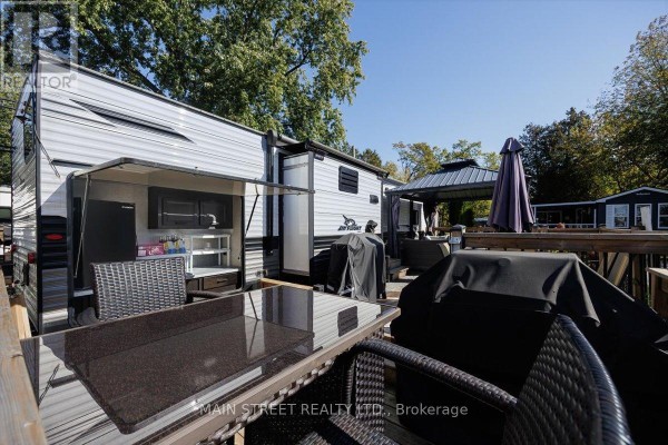 Outdoor kitchen area with a trailer, grill, and glass-top table with chairs. - 15 Hawaiian Circle, Whitchurch Stouffville