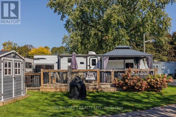 Exterior view of a trailer with a covered deck, outdoor furniture, and a "for sale" sign. - 15 Hawaiian Circle, Whitchurch Stouffville