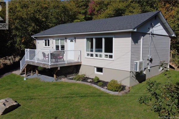 Exterior view of a light beige vinyl-sided house with a dark roof, white deck, and large windows. - 15 Hazen Avenue, Rothesay