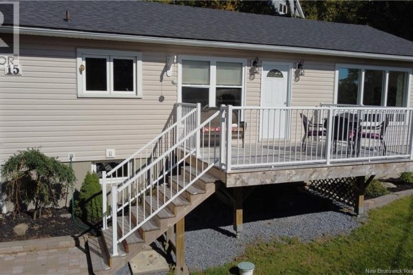 Close-up view of the white deck and stairs with white railings on the side of a beige house. - 15 Hazen Avenue, Rothesay