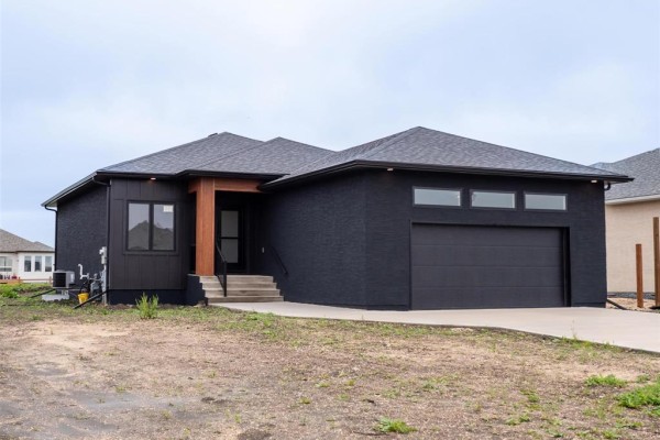 Front exterior of a contemporary dark brick home with a pitched roof and garage door. - 15 Hester Park Cove, Grande Pointe