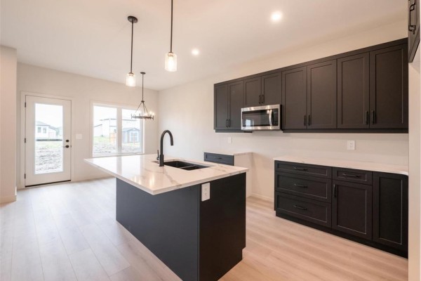 Open concept kitchen and dining area with dark cabinetry, island, and a table with chairs. - 15 Hester Park Cove, Grande Pointe