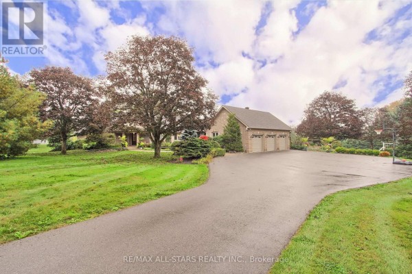 Wide asphalt driveway leads to a brick house with a three-car garage. - 15 Lobraico Lane, Whitchurch Stouffville