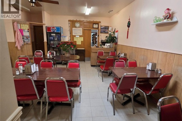 Dining area of a restaurant with red chairs and brown tables, featuring a Pepsi cooler in the background. - 15 Main Street N, Preeceville