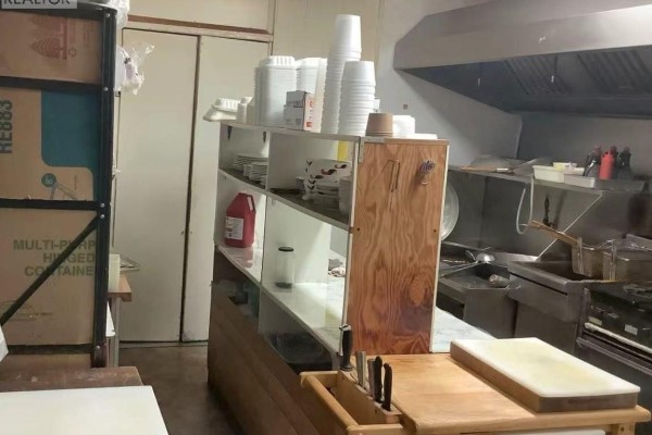 Commercial kitchen area with stainless steel appliances, shelves of supplies, and a wooden counter with knives. - 15 Main Street N, Preeceville