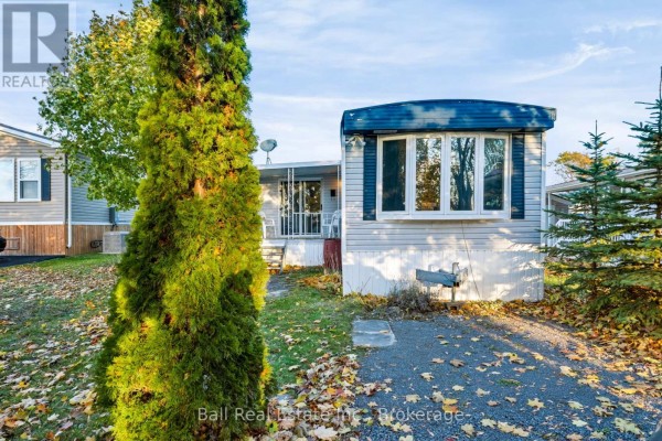 A large evergreen tree in front of a mobile home on a sunny day. - 15 Mcgregor Central Drive, Otonabee South Monaghan