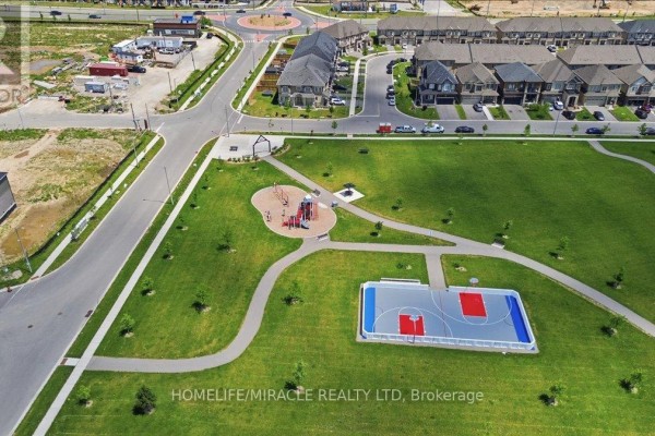 Aerial view of a suburban neighborhood with houses, streets, and a park. - 15 Moriarity Drive, Brant
