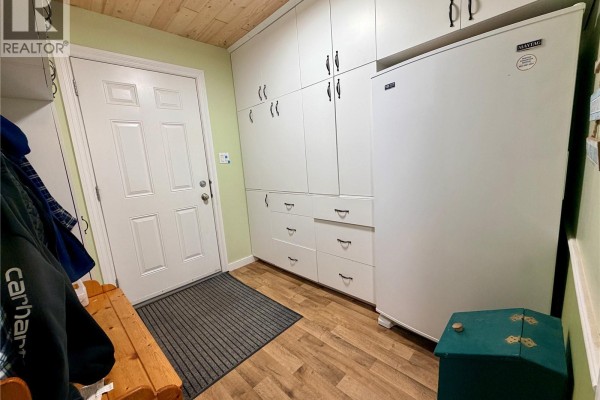 Mudroom entryway with white storage cabinets, door, and wooden bench. - 15 Murray Lake Crescent, Murray Lake