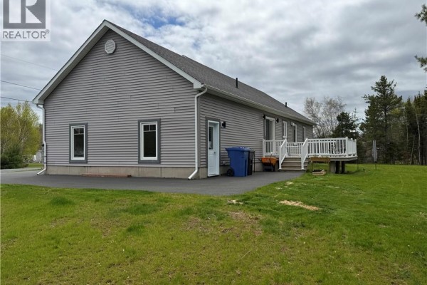 Laundry room with white washer and dryer, ironing board, and a window overlooking greenery. - 15 Rue Girouard, Saumarez