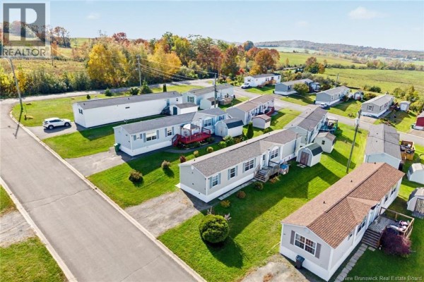 Aerial view of 15 Senator Drive, a light grey manufactured home with multiple other homes in the neighborhood. - 15 Senator Drive, Fredericton