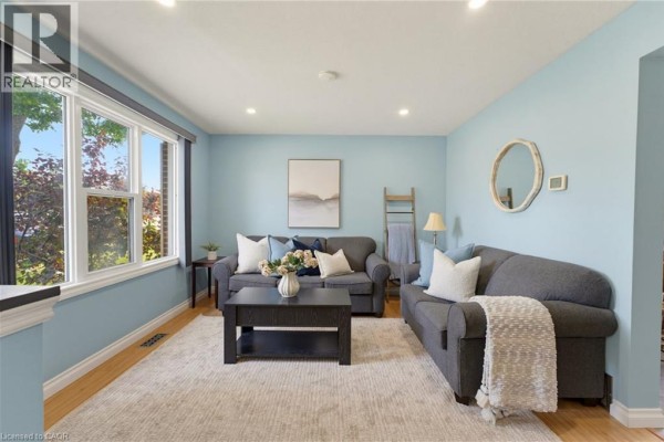 Living room with light blue walls, wood floors, two sofas, a coffee table, and a large window. - 15 Seneca Street S, Cayuga
