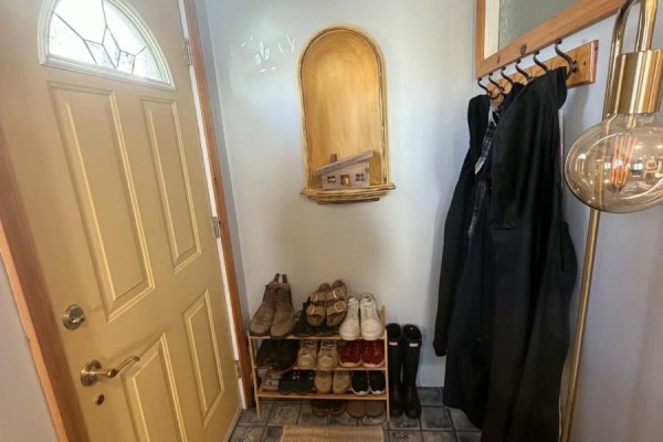 Interior entryway with a yellow door, coat rack with coats, and a shoe rack with shoes. - 15 Spruce Avenue, Happy Valley  Goose Bay
