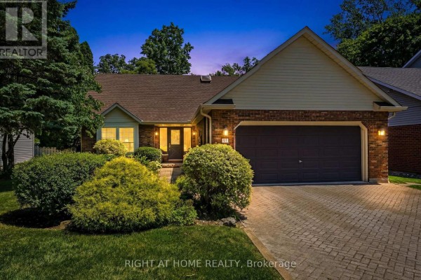 Exterior of a brick home at dusk with illuminated windows and garage. - 15 The Promenade, Niagara On The Lake