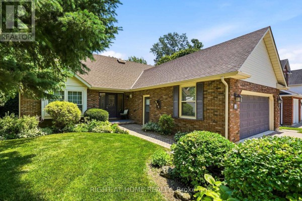 Close-up front view of a brick house with a paved walkway and garden beds. - 15 The Promenade, Niagara On The Lake