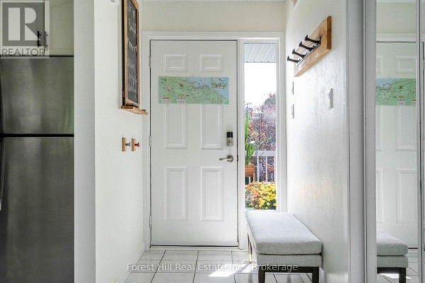 Interior entryway with white doors, tile flooring, coat hooks, and a bench. - 150 - 53 Trott Boulevard, Collingwood