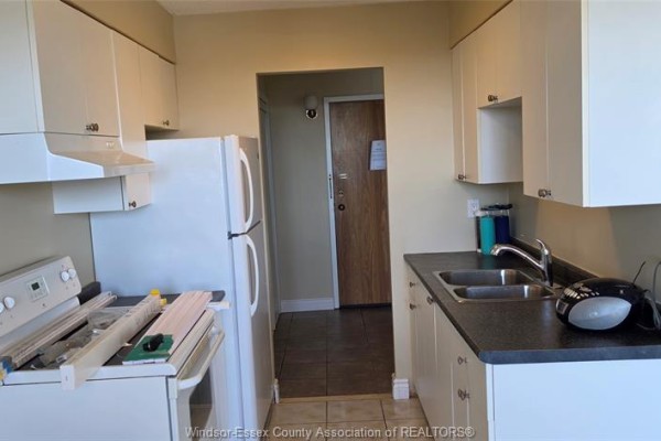 Kitchen with white cabinets, a white refrigerator, a white stove, and a doorway to the hall. - 150 Park West Unit# 1112, Windsor