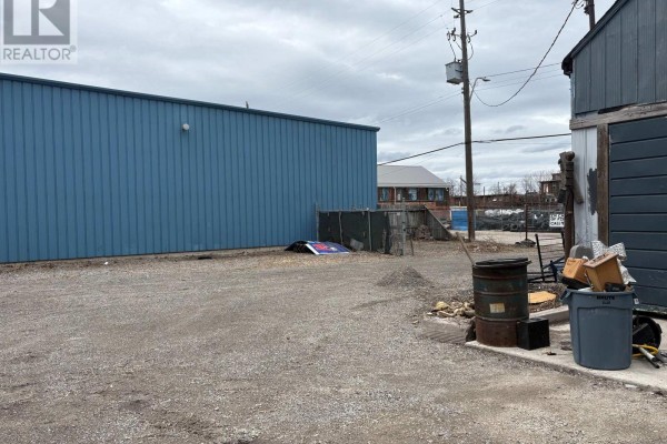 Gravel area adjacent to blue building, with scattered debris and storage containers. - 150 Princess Street, Hamilton