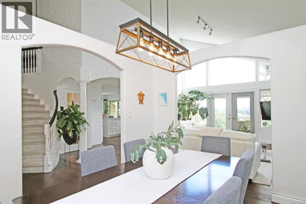 Interior foyer with grand staircase, white banister, and dark wood floors. - 150 Rainbow Cres, Nanaimo