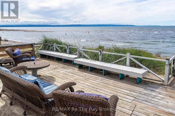 Wooden deck with wicker chairs and benches facing the beach and the calm waters of Georgian Bay. - 150 Santos Lane, Wasaga Beach