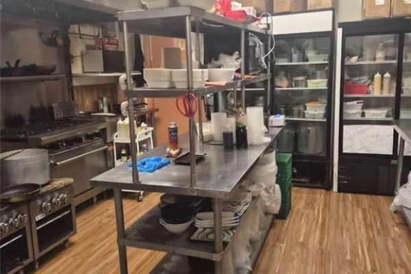 Commercial kitchen with stainless steel worktables, gas range, and two commercial refrigerators. - 150 University Avenue W Unit# 8a, Waterloo