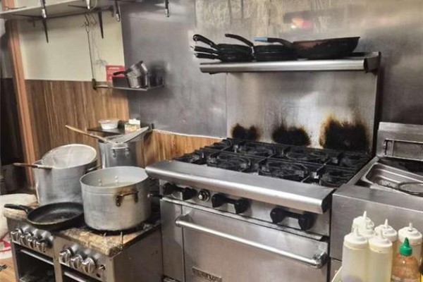 Close-up of a commercial gas range with pots and pans, and stainless steel backsplash. - 150 University Avenue W Unit# 8a, Waterloo