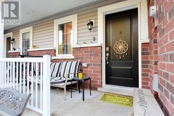 Townhouse front porch with black front door, striped bench seating, and a small table. - 150 Winters Way, Shelburne
