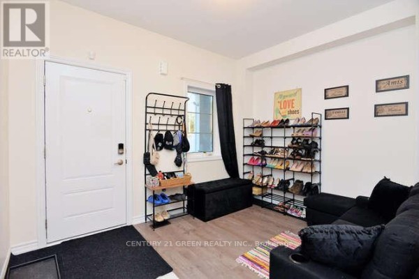 Interior entryway with white door, shoe racks filled with shoes, and a black couch. - 150 Winters Way, Shelburne