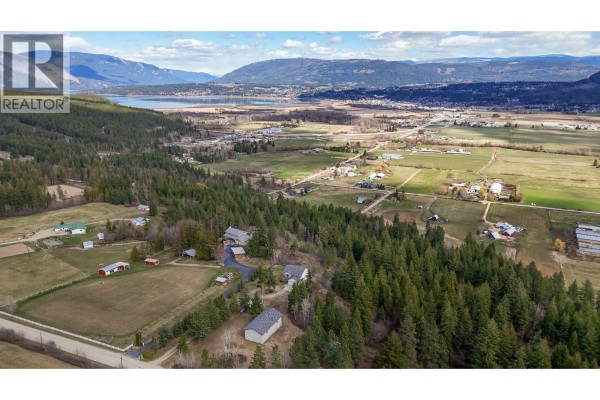 Aerial view of a rural landscape with forested areas, fields, buildings, and rolling hills. - 1500 60 Street Sw, Salmon Arm