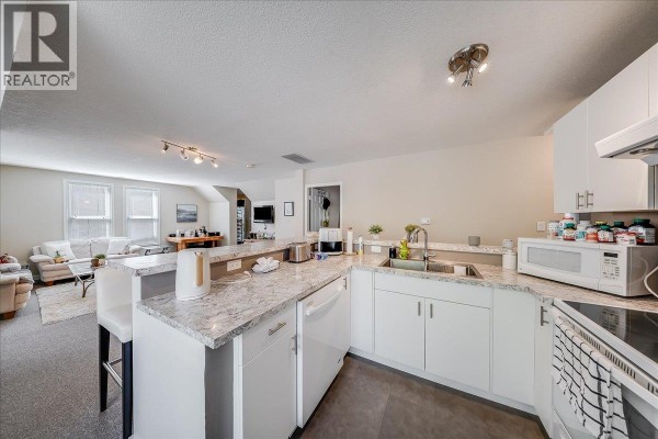 Kitchen with white cabinets, granite countertops, sink, and appliances. - 1500 Cedar Avenue, Trail