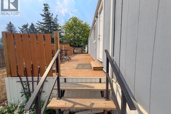 Wooden stairs leading up to a wooden deck with two chairs and a table. - 1500 Spring Street Unit# 6b, Merritt