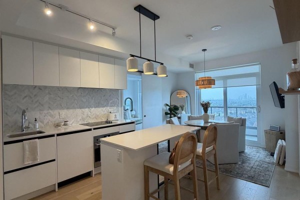 Open concept kitchen and dining area with white cabinets and island seating. - 1501 - 7950 Bathurst Street, Vaughan