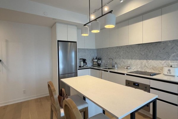 Modern kitchen with stainless steel appliances, white cabinets, and a breakfast island. - 1501 - 7950 Bathurst Street, Vaughan
