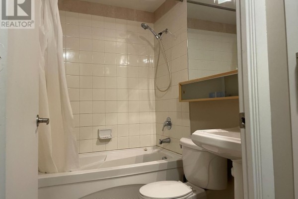 Bathroom with a white bathtub, tiled walls, sink, and a shower curtain. - 1501 - 85 Bloor Street E, Toronto