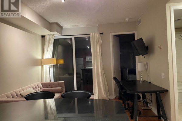 Living area with sofa, desk, and a sliding glass door leading to a balcony. - 1501 - 85 Bloor Street E, Toronto