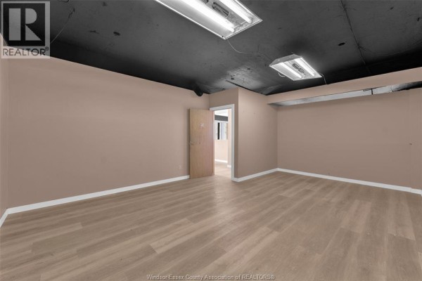 Empty room with light-colored walls, wooden flooring, and a doorway leading to another space. - 1501 Howard Avenue Unit# 201c, Windsor