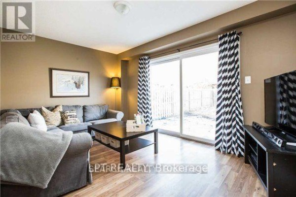 Living room with a sectional sofa, patterned curtains, and a sliding glass door to the backyard. - 1501 Rankin Way, Innisfil