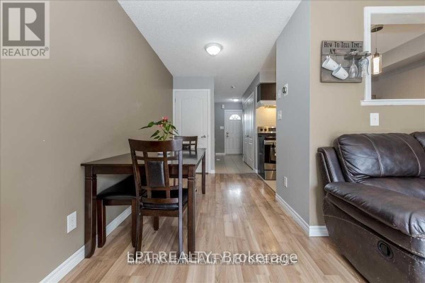 Dining area with a dark wood table and chairs, looking down a hallway towards the kitchen. - 1501 Rankin Way, Innisfil