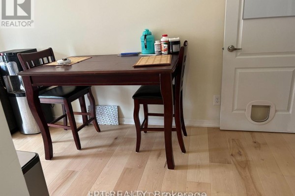 Small dining table with two chairs next to a closed white door with a pet door. - 1501 Rankin Way, Innisfil