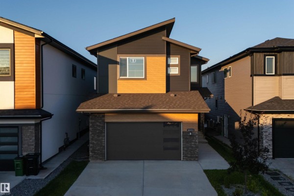 Front view of the modern two-story house with a dark grey roof and wood accents. - 15011 10 St Nw, Edmonton