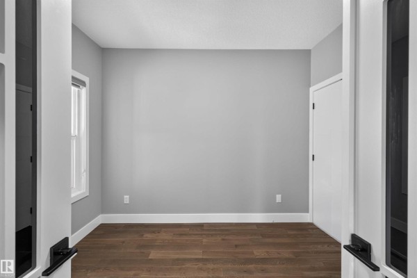 Empty room with grey walls, a window, and a white closet door on the right. - 15011 10 St Nw, Edmonton