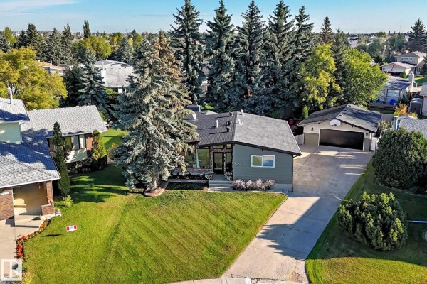 Aerial view of a green-roofed house surrounded by mature trees and a paved driveway. - 15011 55 St Nw, Edmonton